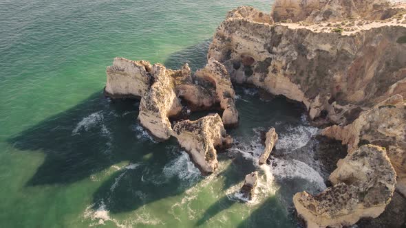 Limestone cliffs that form the coastline Lagos, Algarve. Waves washing on rocks. Orbiting shot alt