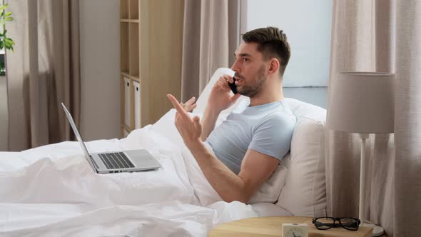 Man with Folder Calling on Phone in Bed at Home