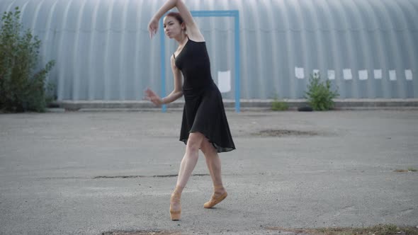 Camera Approaches To Slim Young Ballerina Dancing on Tiptoes on Urban Wasteland alt