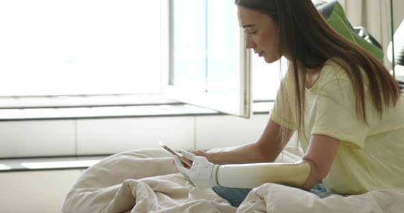 Girl with Bionic Arm Using Phone Reading Social Media and Chatting in Bed Woman with Disability alt