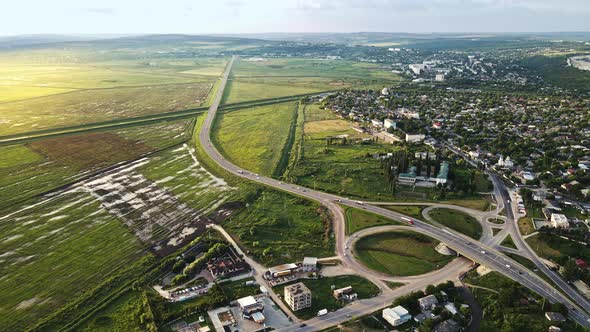 Aerial drone view of a village and road with cars, greenery, fields, Moldova alt