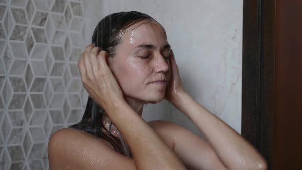 Young Tanned Woman is Taking a Shower with Close Eyes
