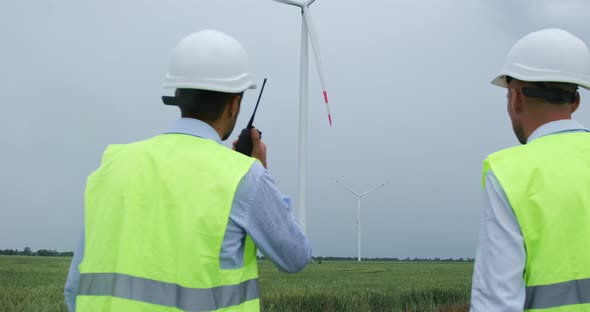 Engineers toolkit come to wind turbine generating electricity in field.