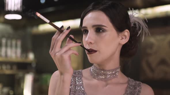 Portrait of a Young Attractive Woman in a 1920s Style Smoke Cigarette at the Bar alt