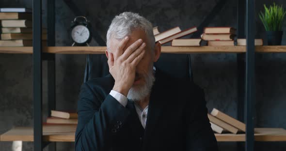 Shocked Mature Businessman Looks at Camera and Covers His Face with His Hands in Surprise at the alt
