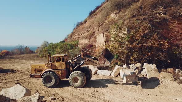Bulldozer is Working Near Sand Quarry on the Background of Stones alt