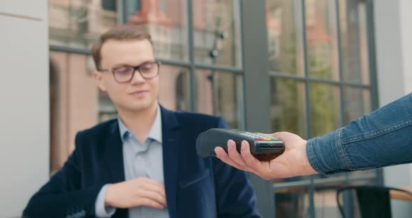The Businessman is Taking Out a Credit Card and Paying for the Order Via a Contactless Payment