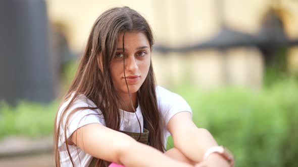 Young Beautiful Woman in the Street Stares Serious at Camera alt
