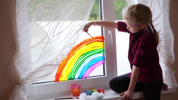 Girl Painting Rainbow on Window During Covid19 Quarantine at Home alt