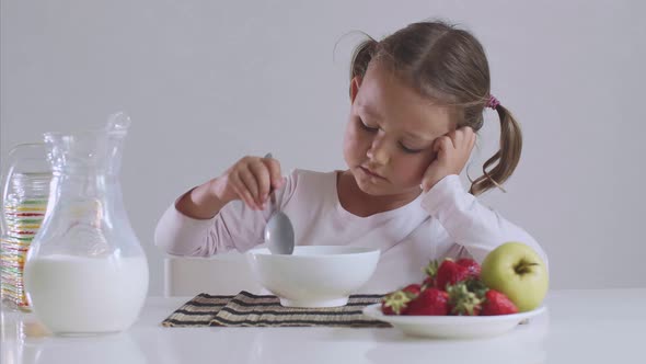 Bored Little Girl Doesn't Want To Eat Cornflakes with Milk for Breakfast.