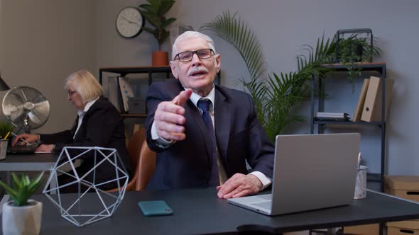Friendly Senior Businessman Outstretching Hand to Camera Offering Handshake Greeting with Smile alt