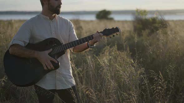Spanish Guitarist Performing in the Grassy Field in Autumn Playing Chords and Singing Song on Black alt
