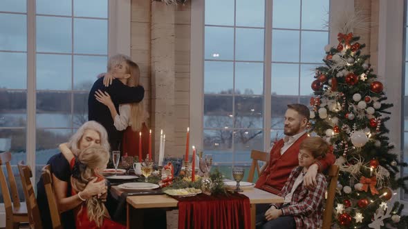 Grandparents Hug with Their Children on Christmas Eve at the Festive Table alt