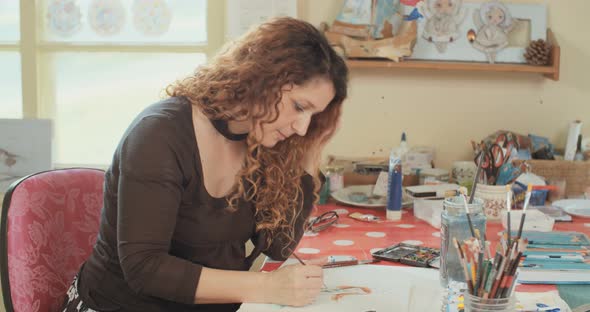 Female artist painting in her studio with water colors and pencils alt