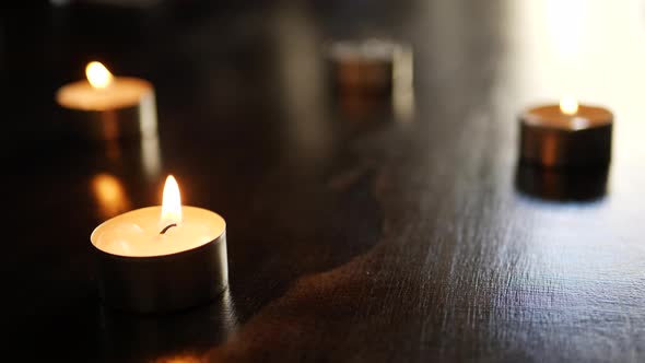 Blowing out and extinguishing four tealight candle flames and turning them to smoke in slow motion w alt