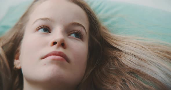 Close up young blonde woman looking bored while laying on her back alt