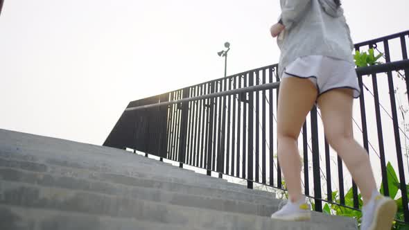 4K Asian woman running up stairs while jogging at public park in the morning. alt