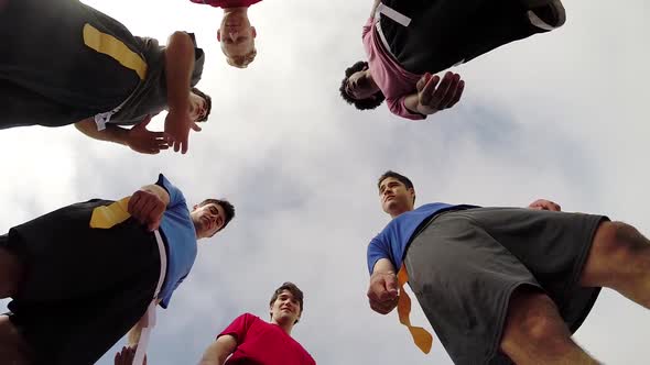 A group of young men playing flag football on the beach. alt