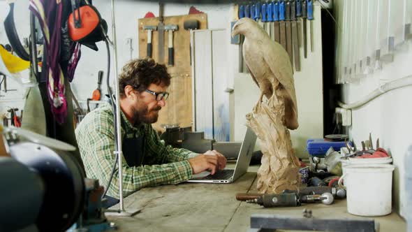 Craftsman using laptop at desk 4k alt