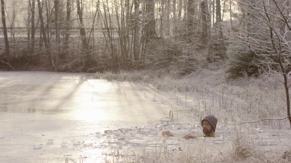 ZOOM IN - A cyclist rides past as the ice bather sits in freezing cold water alt