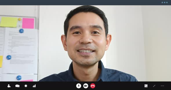 South East Asian man having remote video call meeting online saying hi