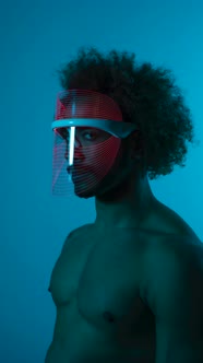 Timelapse shot of man wearing light therapy mask against blue wall alt