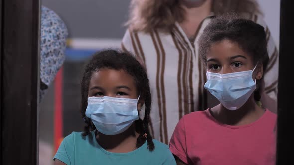Curly Girls in Face Masks with Parents By Window alt