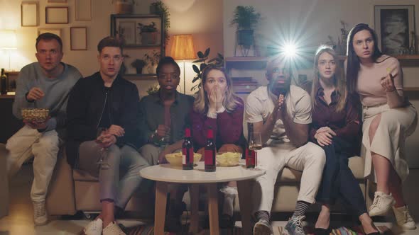 Group of People Watching Scary Movie at Home alt