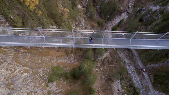 Girl Crossing a Footbridge Spanning a Ravine alt