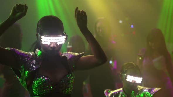 Group of People Dance in Disco Night Club to the Beat of Music From DJ on Stage alt