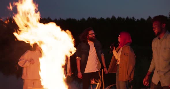 Friends Put Branches on the Fire at Which They are Having Fun the Scenery of the Beach Lake Warm alt