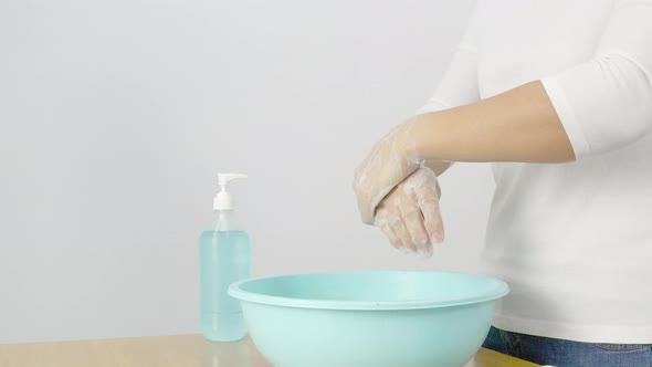 Women wearing white shirts and washing their hands with soap or alcohol gel.