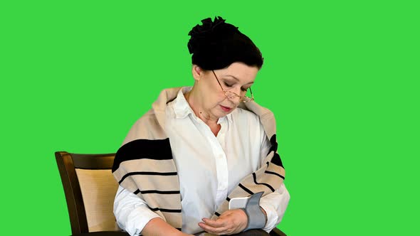 Senior Woman Measuring Her Blood Pressure on a Green Screen Chroma Key alt