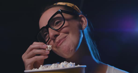 Woman watching a romantic comedy movie at the cinema and eating popcorn, entertainment concept