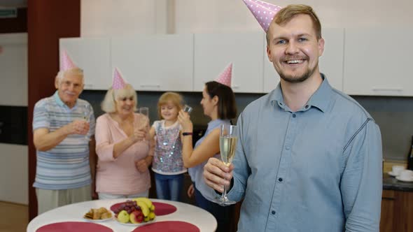 Birthday Man Holding Glass of Champagne Looking at Camera. Father Celebrating Anniversary Holiday alt
