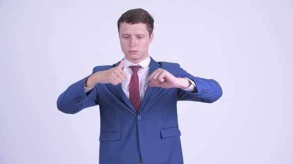 Confused Young Businessman Choosing Between Thumbs Up and Thumbs Down alt