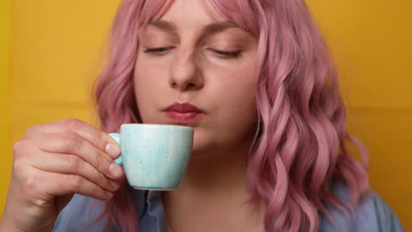 Portrait of Joyful Young Woman with Pink Hair Hairstyle Enjoying a Cup of Coffee Isolated Over