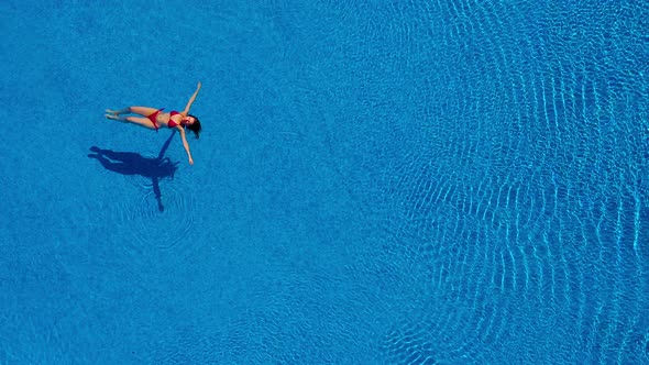 View From the Top As a Woman in a Red Swimsuit Swims Backstroke in the Pool alt
