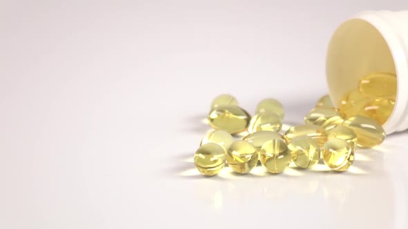 Fish Fat Oil Capsules Are Scattered Off of the Medical Jar on White alt