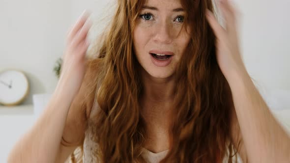 woman suddenly wakes up on  bed in morning in bedroom and puts head in hands alt