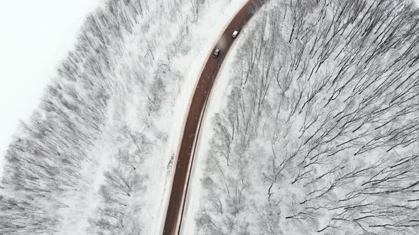 Car drives through a slippery snow covered intersection. Flying above a car driving down icy road