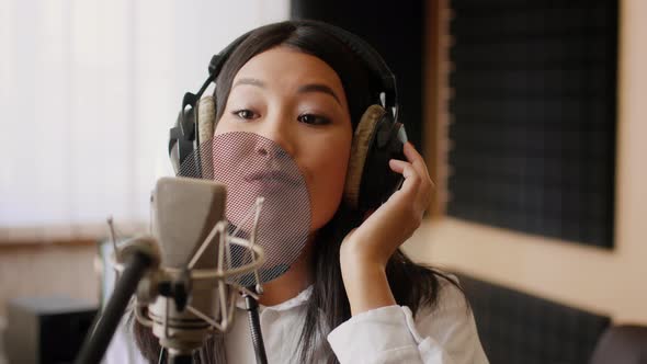 Energetic Young Asian Female Vocalist Singing In Microphone In Music Studio alt