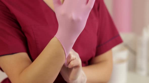 Cosmetologist Puts on Pink Protective Gloves Before the Procedure of Sugaring alt