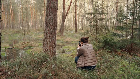 A Young Woman Walking in the Park Taking Pictures of the Landscape on Her Phone