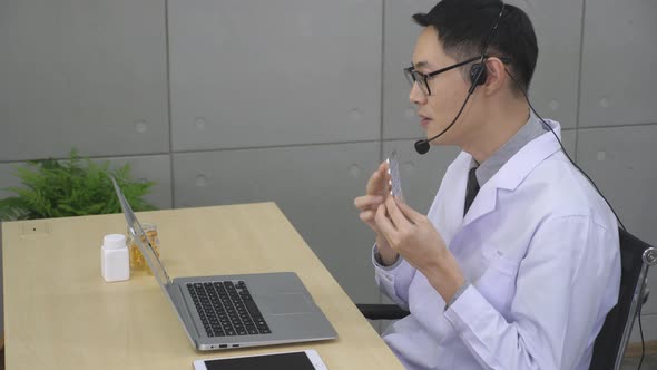 Asian male doctor working, describing how to use medicine. Telemedicine concept alt