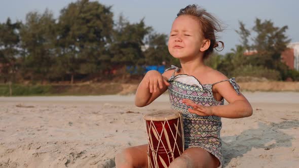 Cute Little Child Girl Playing Drums on Sandy Beach