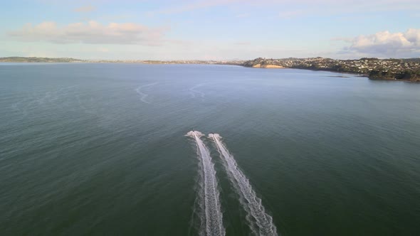 Flying quickly behind 2 jet skis along the coast of Orewa beach in New Zealand at sunset alt