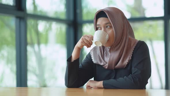 Muslim Asian working women drinking coffee in the morning with a happy face. alt
