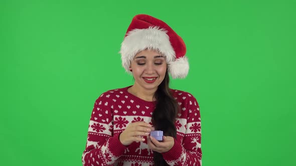 Portrait Girl in Santa Claus Hat Is Opening Small Box with Surprise and Is Disappointed with What alt