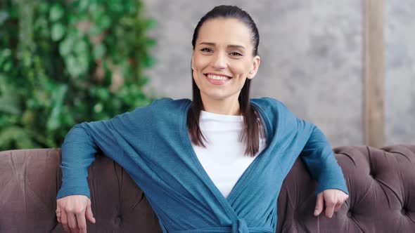 Confident Smiling Caucasian Charming Woman Sitting on Couch Posing and Looking at Camera alt